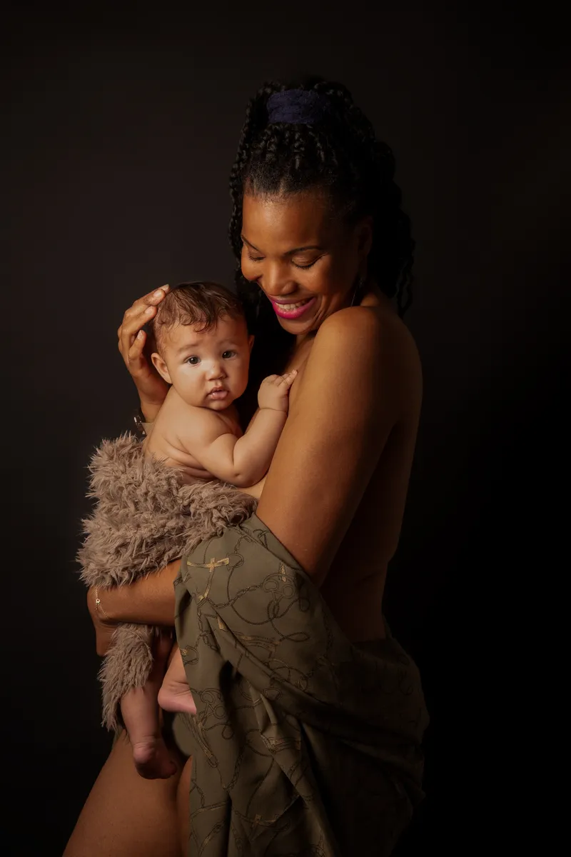 Femme afro avec son bébé dans les bras. Lumière clair-obscur